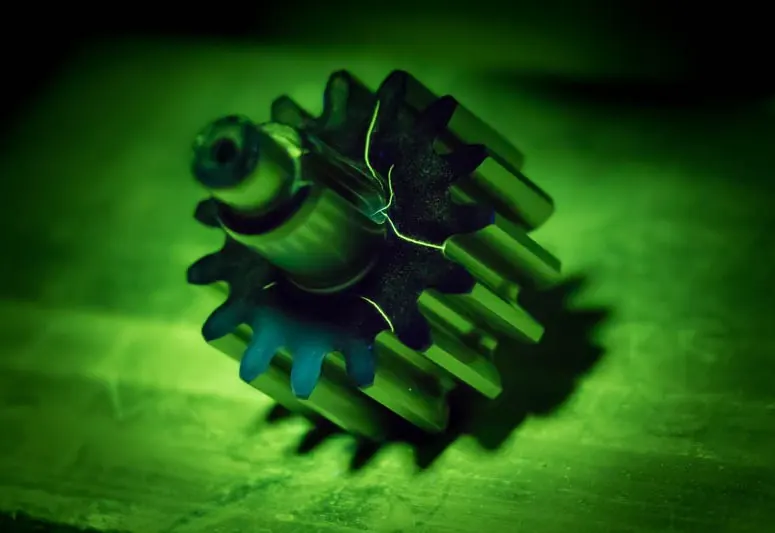 Gear under UV light showing fluorescent penetrant indications