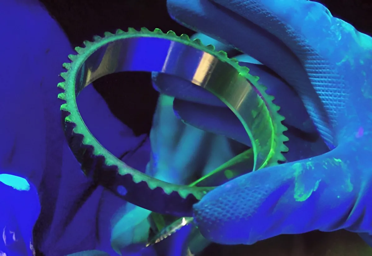 Inspector checking a toothed ring under UV light
