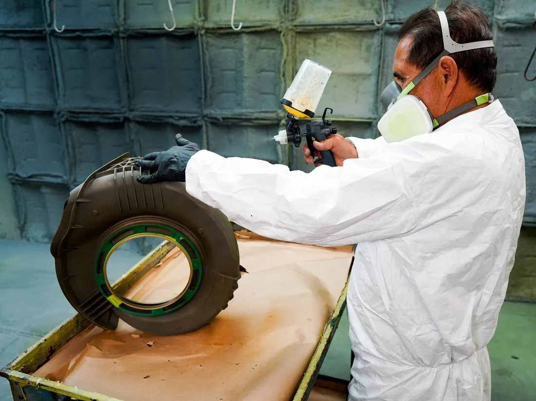 Painter spray-coating a part in the paint booth